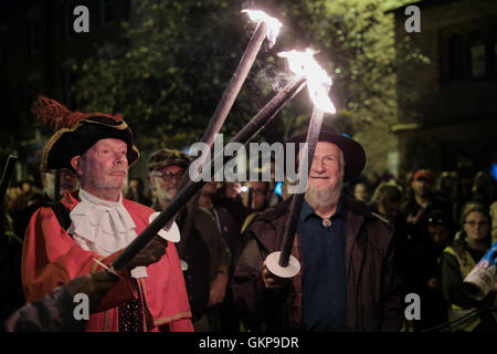 Bridport Torchlight Procession, Bridport, Dorset, UK. 21st Aug, 2016. Bridport Town Crier leads thousands of blazing torches from Bridport's Bucky Doo Square to West Bay's East Cliff where music, fireworks and a giant bonfire helped celebrate the end of Bridport's Carnival week. The Bridport Carnival first started in 1911, was abandoned in 1920 then resurrected in 1971 and has been a popular annual event for locals and visitors since. Credit:  Tom Corban/Alamy Live News Stock Photo