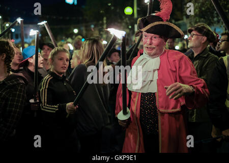 Bridport Torchlight Procession, Bridport, Dorset, UK. 21st Aug, 2016. Bridport Town Crier leads thousands of blazing torches from Bridport's Bucky Doo Square to West Bay's East Cliff where music, fireworks and a giant bonfire helped celebrate the end of Bridport's Carnival week. The Bridport Carnival first started in 1911, was abandoned in 1920 then resurrected in 1971 and has been a popular annual event for locals and visitors since. Credit:  Tom Corban/Alamy Live News Stock Photo