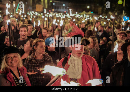 Bridport Torchlight Procession, Bridport, Dorset, UK. 21st Aug, 2016. Bridport Town Crier leads thousands of blazing torches from Bridport's Bucky Doo Square to West Bay's East Cliff where music, fireworks and a giant bonfire helped celebrate the end of Bridport's Carnival week. The Bridport Carnival first started in 1911, was abandoned in 1920 then resurrected in 1971 and has been a popular annual event for locals and visitors since. Credit:  Tom Corban/Alamy Live News Stock Photo