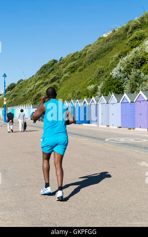 Bournemouth, Dorset, UK 23 August 2016. Runner jogging along the promenade past beach huts at  Bournemouth beach on a hot sunny day Credit:  Carolyn Jenkins/Alamy Live News Stock Photo