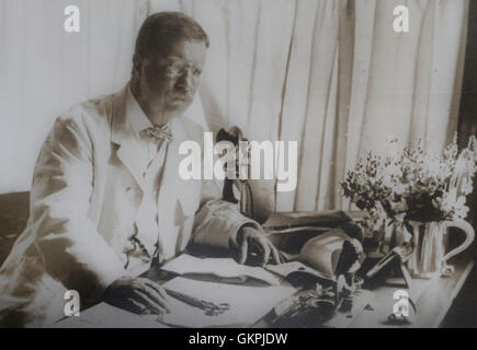 Theodore Roosevelt working at his desk in the Library in June 1905. He placed his desk in the bay window so he could watch as visitors arrived to the house. Sagamore Hill, Oyster Bay, New York Stock Photo