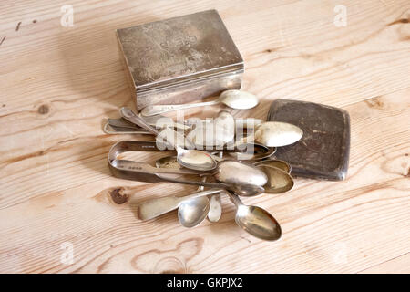 A collection of unwanted early 20th Century silver items an a wooden table top for disposal Stock Photo