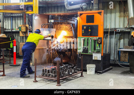 workman grinding and cutting away cast metal components from its 'casting' tree. Stock Photo