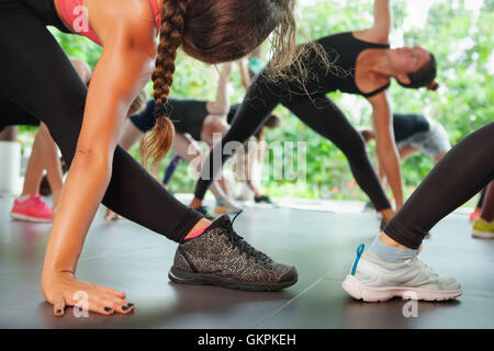 Sports workout background. Back view of women legs in sneakers. Group of sporty people training with fitness instructor Stock Photo