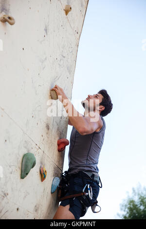 Young fit man doing exercise in mountain climbing on indoor practice wall Stock Photo