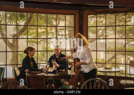 Waitress serving wine to couple dinging at Waterfront Depot restaurant overlooking the Siuslaw River in Old Town, Florence; Oreg Stock Photo