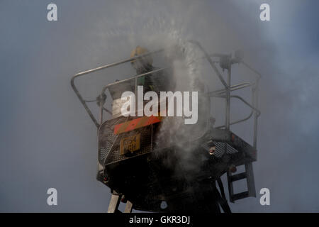 Two London firefighters operating a height platform at the scene of a fire in London Stock Photo