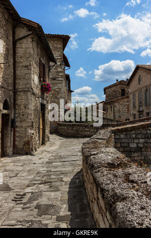 Vertical view of a historic stone-paved walkway with parapet and medieval houses under a cloudy sky in old town Gubbio, Umbria region, Italy Stock Photo