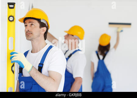 Building teamwork concept - group of smiling builders in hardhats with tools indoors Stock Photo
