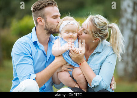 Portrait of parents kissing their baby girl Stock Photo