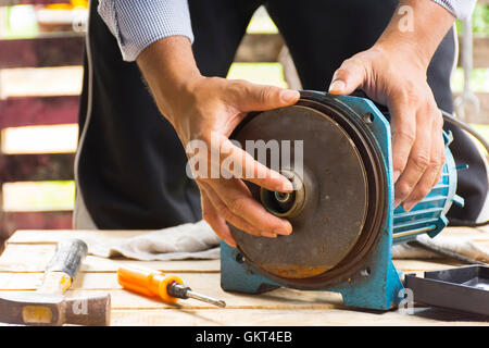 Electric motor  and man working equipment repair on wooden floor background.Background mechanic or equipment.Zoom in Stock Photo