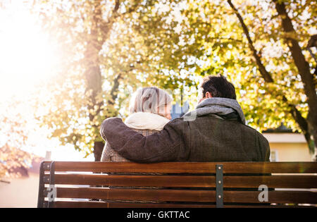 Senior couple sitting on bench, autumn nature. Rear view Stock Photo