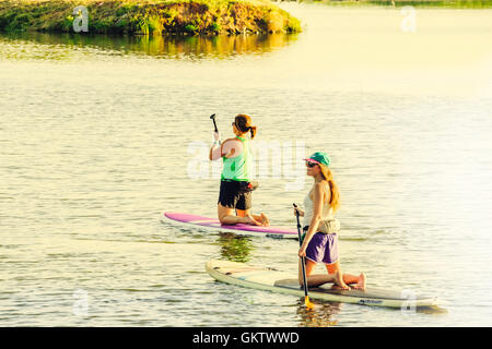 Two young Caucasian women enjoy paddleboarding on the North Canadian river near Bethany and Oklahoma City in Oklahoma, USA. Stock Photo