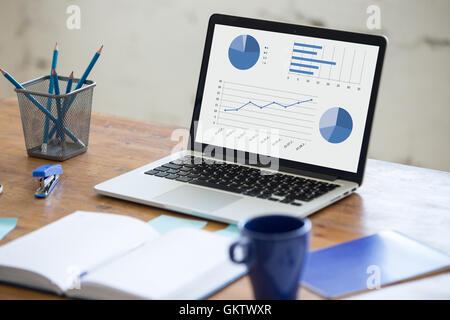 Home office interior in loft space. Workplace with wooden table, office supplies, documents, organizer and laptop. Modern office Stock Photo