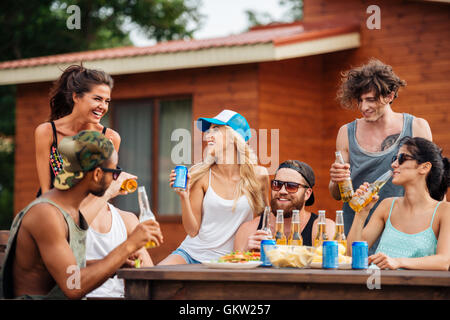 Group of cheerful young people drinking beer and soda and laughing outdoors Stock Photo