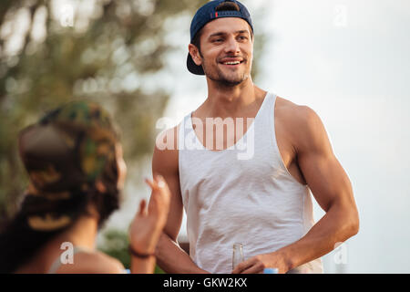 Potrait of smiling handsome young man in cap standing outdoors Stock Photo