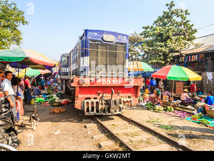 Approaching train passing through the traditional local Ya Zay Railway Bazaar, an outdoor market held on railway tracks, Mandalay, Myanmar (Burma) Stock Photo