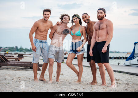 Portrait of smiling young woman standing with men on the beach Stock Photo
