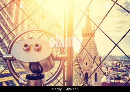 Vintage toned tourist binoculars over Vienna at sunset, view from the north tower of St. Stephen's Cathedral, focus on binocular Stock Photo