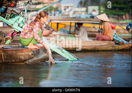 Woman doing laundry back of houseboat on Mekong Delta Stock Photo