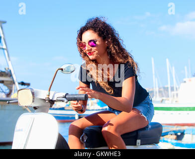 Young Italian Woman with Long Curly Hair on Vespa Stock Photo