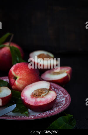 Plate of fresh nectarines on dark background Stock Photo