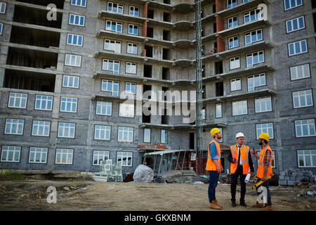 Team of co-workers standing on construction site and discussing new building Stock Photo