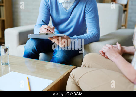 Psychologist making notes while listening to his patient Stock Photo