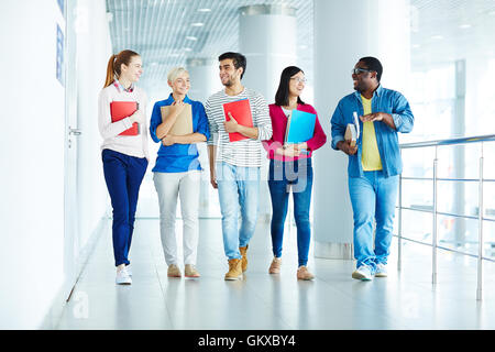 Group of intercultural students walking down corridor after classes Stock Photo