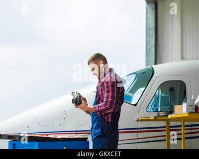 Young repairman in uniform working in hangar Stock Photo