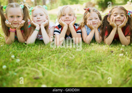 Group of friendly kids lying on the lawn Stock Photo