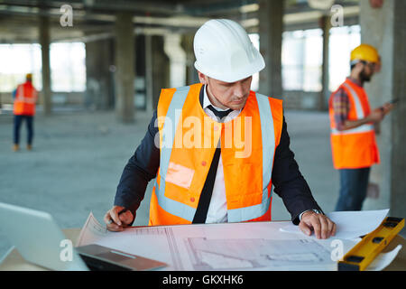 Constructor in uniform and helmet looking at sketch Stock Photo