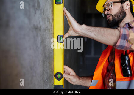 Man in uniform measuring level of wall flatness Stock Photo