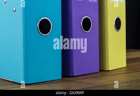 Close up photo of three bright colored lever arch files on a desk Stock Photo