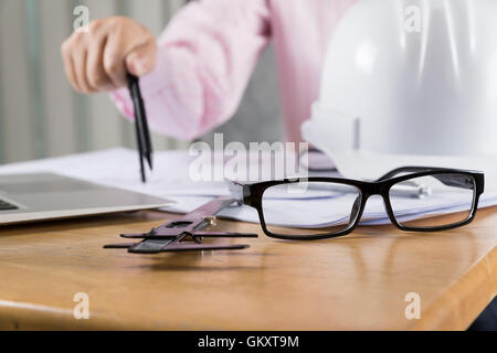 architect hand holding compass working on construction engineering project blueprint Stock Photo