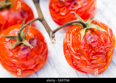 Tomatoes on the vine baked in an oven, served on a wooden picnic table. Stock Photo