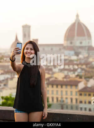 Young Teen  takes a selfie at sunset in Florence, Cathedral of Santa Maria del Fiore on the background. Stock Photo