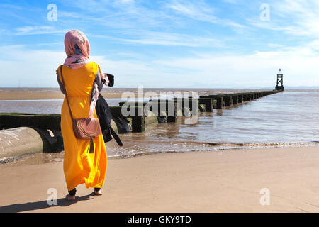 Crosby, Merseyside, UK. 24th August, 2016.  UK Weather: Sunny day in Crosby, Liverpool, UK. 24/08/16.  A woman in bright yellow looks out over the Irish Sea, taking in the great views over to the north wales coastline.  Gorgeous blue skies and warm sunshine over Liverpool with temperatures around a comfortable 22˚C.  A last gasp of summer heat will encompass much of England & Wales till Thursday.  Credit:  Cernan Elias/Alamy Live News Stock Photo