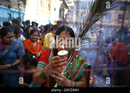 Lalitpur, Nepal. 25th Aug, 2016. A Nepalese devotee holds butter lamps while offering prayers during celebrations of Janmashtami festival or birth anniversary of Deity Krishna near Krishna Temple in Patan Durbar Square, Lalitpur on Thursday, August 25, 16. Credit:  Skanda Gautam/ZUMA Wire/Alamy Live News Stock Photo