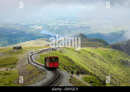 Train climbing up on Mt Snowdon Mountain Railway line above Clogwyn Station and people walking on Llanberis path in Snowdonia Wales UK Stock Photo