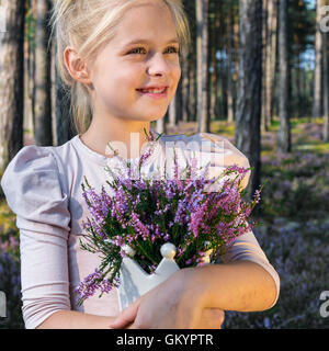 Beautiful girl in the forest holding in a vase with heather. Stock Photo