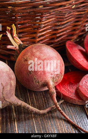 Beetroots on wooden table with old woven basket in background Stock Photo