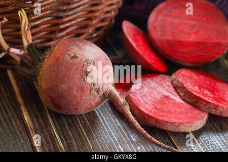 Beetroots on wooden table with old woven basket in background Stock Photo