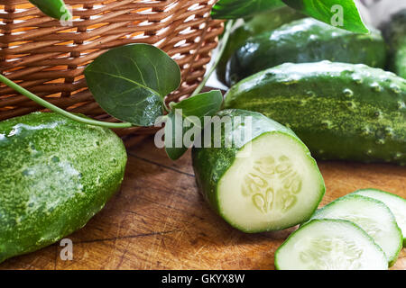Fresh cucumbers scattered around on wooden cutting board Stock Photo