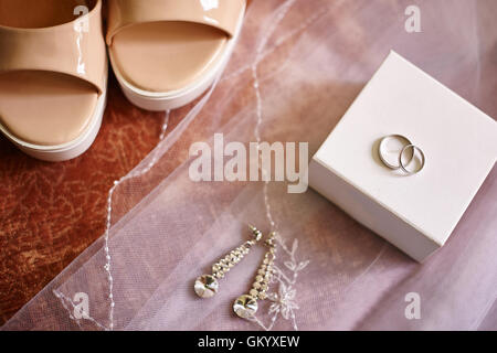 Wedding rings and earrings on a white veil of bride Stock Photo
