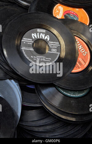 Old records pile of dusty 45s scratched 7' vinyl singles background. Selective focus. Stock Photo