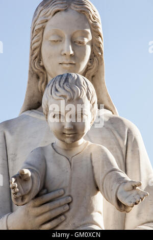 Statue of holy Virgin Mary mother of the child Jesus on blue sky. Stock Photo