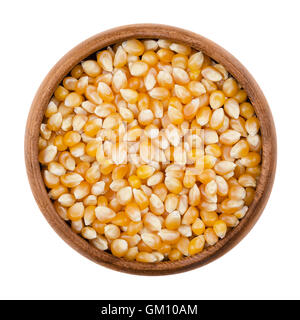 Unpopped popcorn in a wooden bowl on white background. A type of corn that expands from the kernel and puffs up when heated. Stock Photo