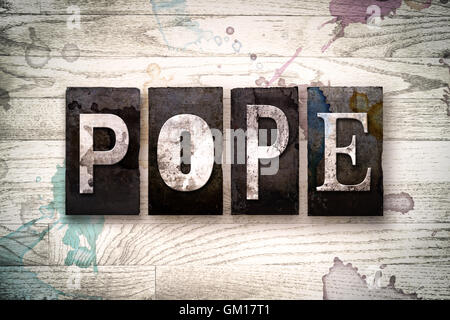 The word 'POPE' written in vintage dirty metal letterpress type on a whitewashed wooden background with ink and paint stains. Stock Photo