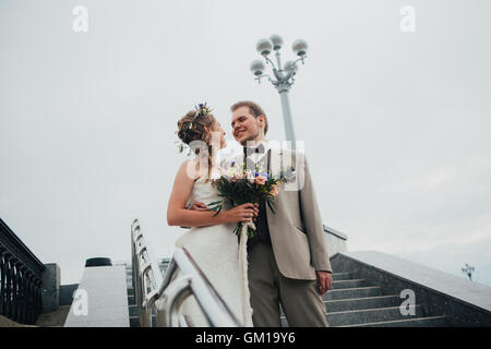 young bride and groom on the background of the stairs. Stock Photo